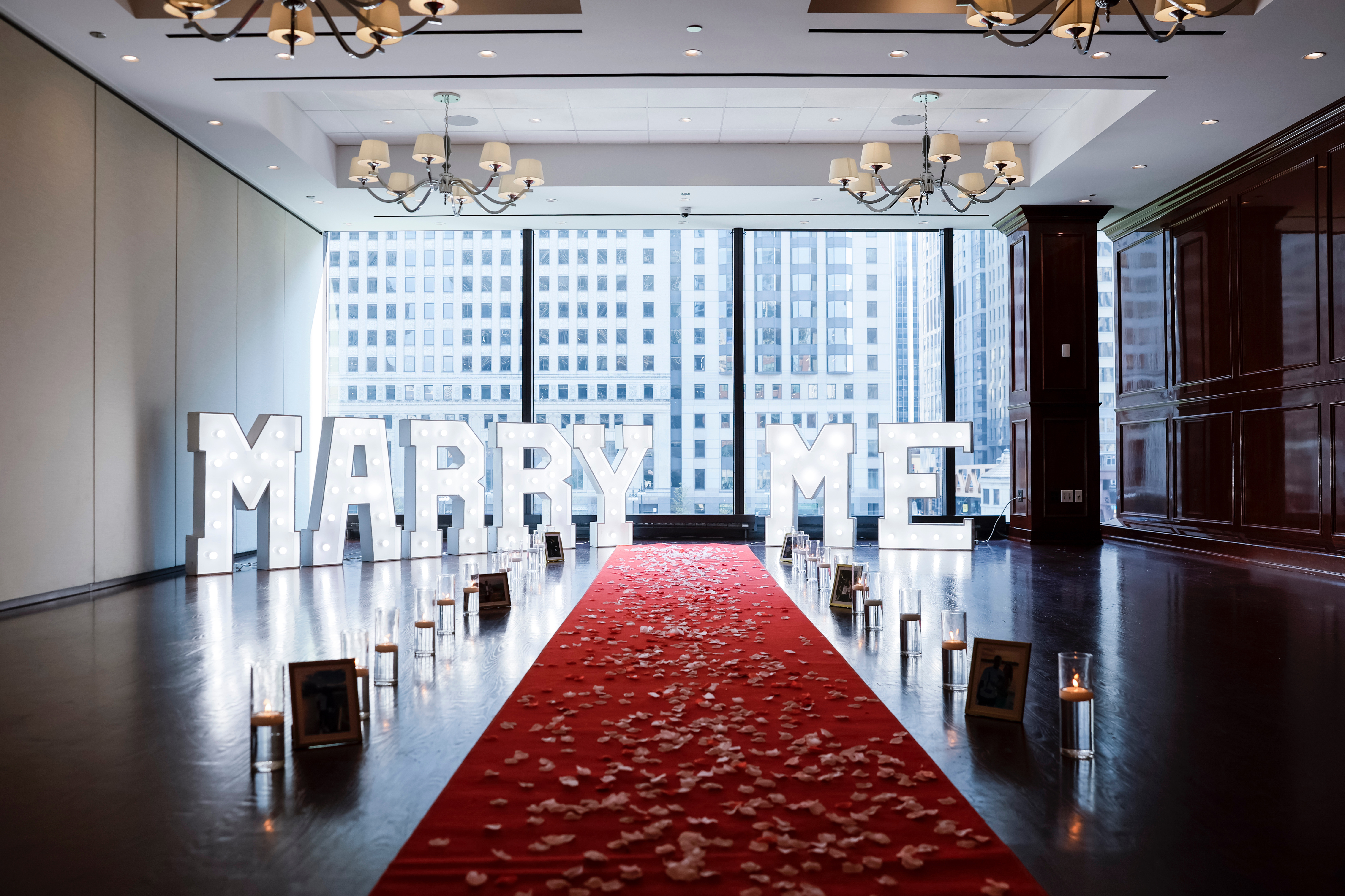 Chicago proposal setup — red carpet with MARRY ME marquee letters, candles, and floral arrangements